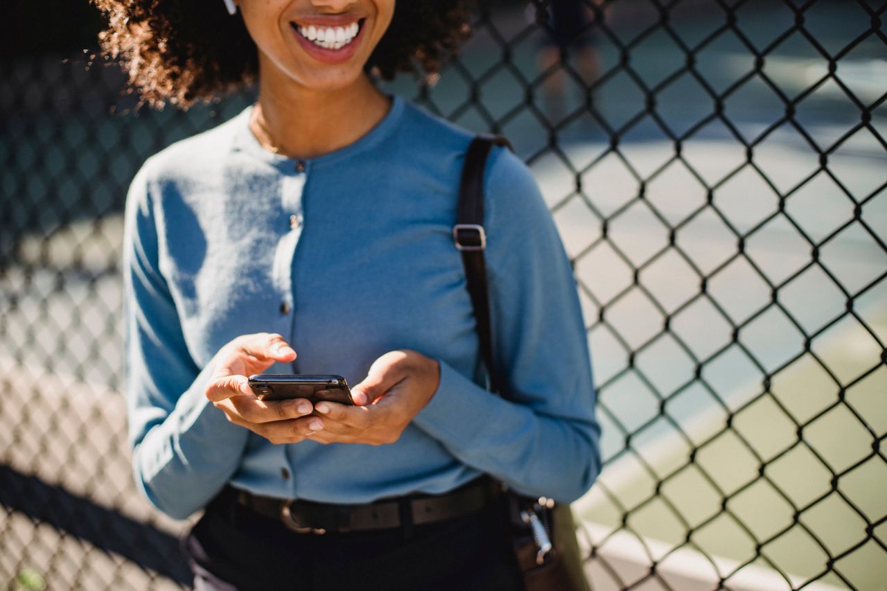 A smiling woman checking her earnings on her phone